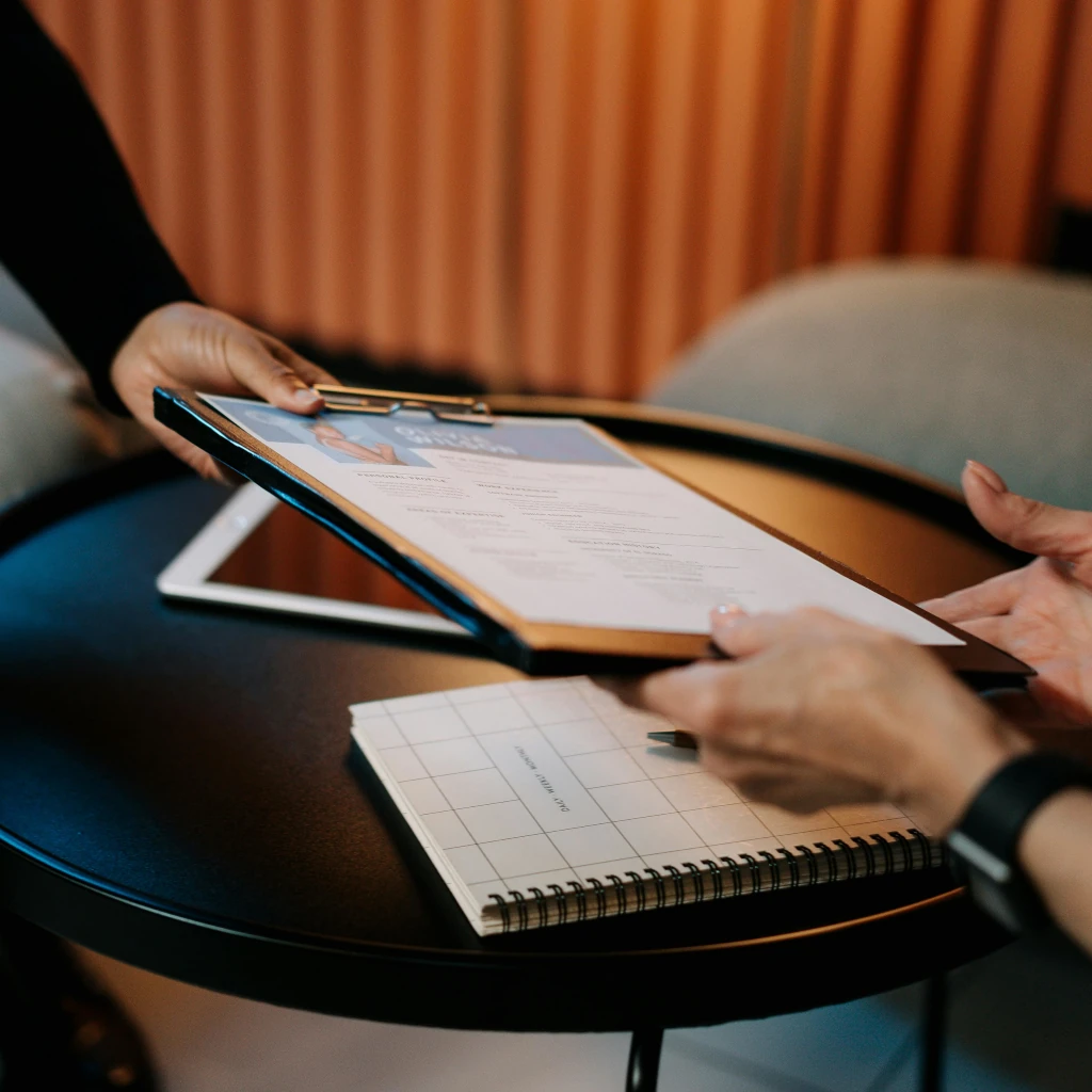 Imagem de uma pessoa passando o currículo de um candidato para o recrutador ilustrando o texto O que são Recursos Humanos e as suas Funções​