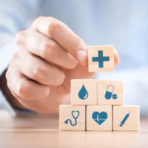 Imagem de uma mão empilhando pequenos blocos de madeira com símbolos que remetem à saúde ilustrando o texto Prevenção e Cuidado em Saúde Mental