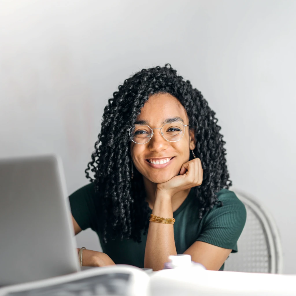 Prevenção e Cuidado em Saúde Mental Halo Inteligência em Gestão Imagem de uma mulher sorrindo em um ambiente de trabalho com um computador à frente ilustrando o texto Prevenção e Cuidado em Saúde Mental Halo Inteligência em Gestão