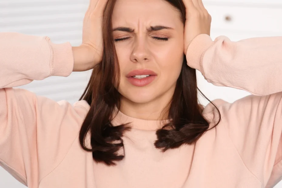 Mulher com expressão de esgotamento mental segurando a cabeça, ilustrando os impactos dos riscos psicossociais no ambiente de trabalho.
