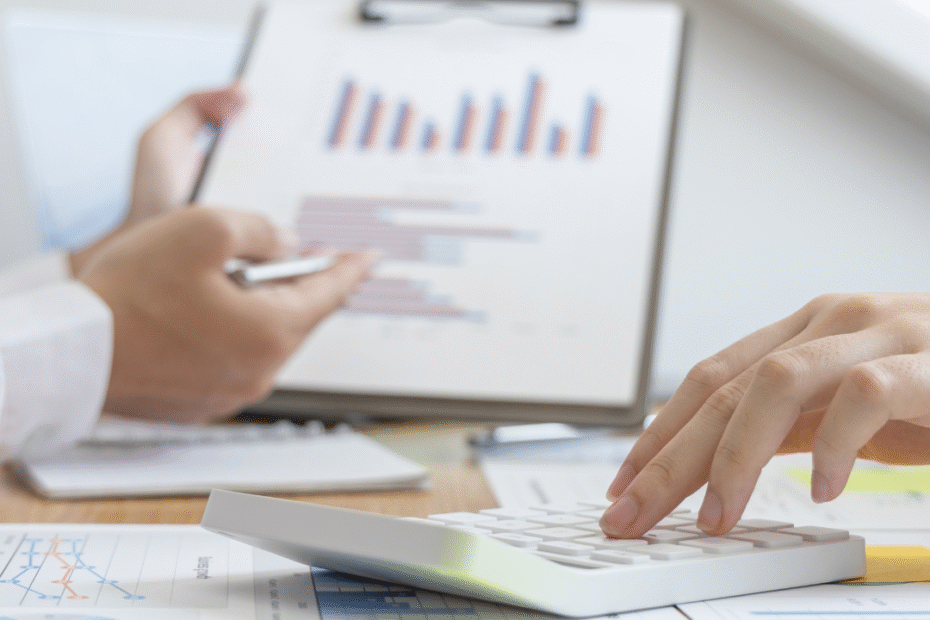 Imagem de uma pessoa mostrando uma prancheta com gráficos que indicam o crescimento da empresa e em primeiro plano uma pessoa utilizando uma calculadora ilustrando o texto Consultoria empresarial em Passos (MG)
